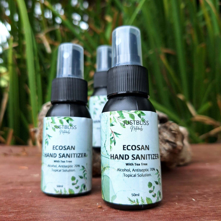 EcoSan 70% Alcohol Hand Sanitizer with Tea Tree Essential Oil, 50ml bottle on wooden surface with green background.