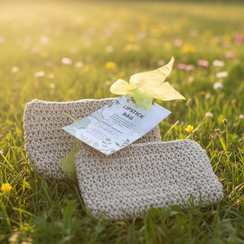Beige crochet lipstick bag with a green bow and label on a dark surface