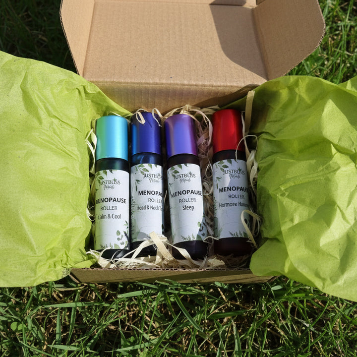 Four menopause roller bottles in a cardboard box with green tissue paper.