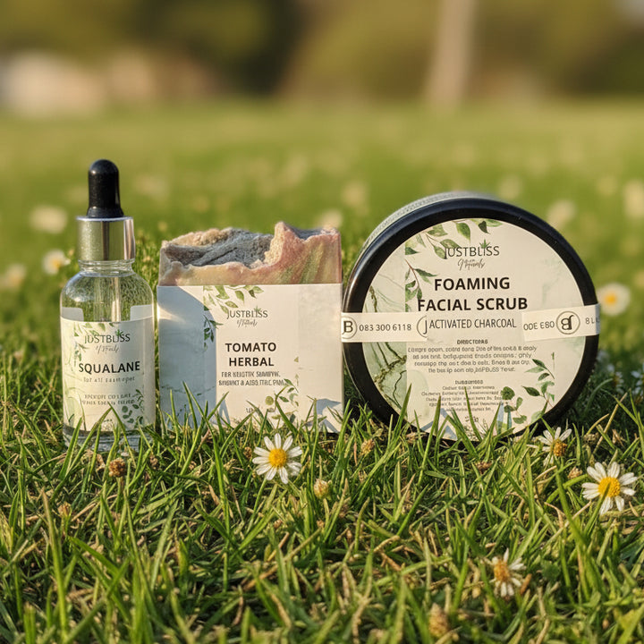 Collection of Justusius skincare products including a bottle, soap, and scrub on a wooden surface with a natural background.