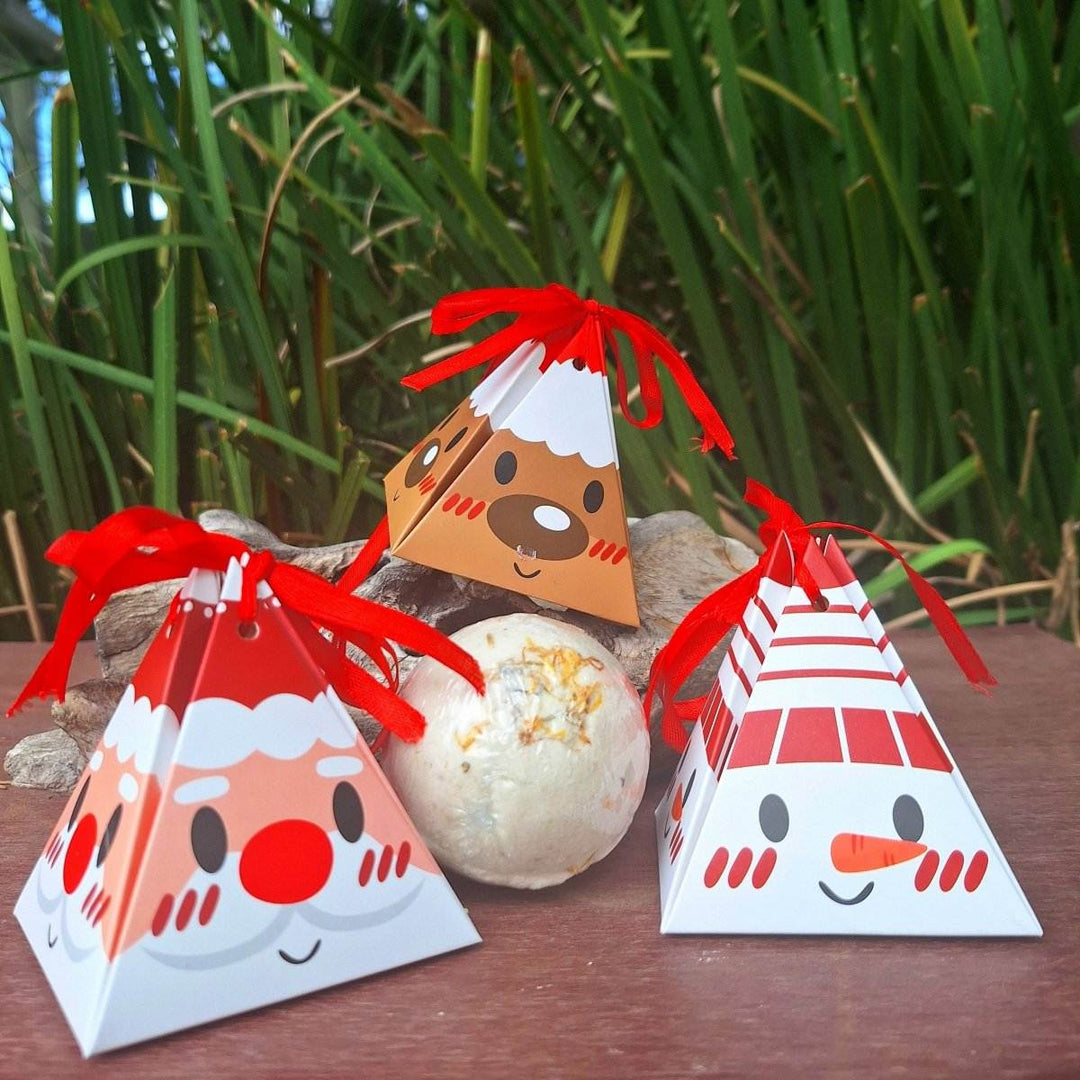 Christmas themed bath bomb with festive packaging, surrounded by greenery.