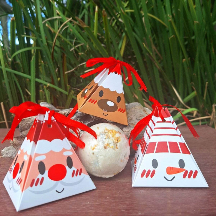 Christmas themed bath bomb with festive packaging, surrounded by greenery.