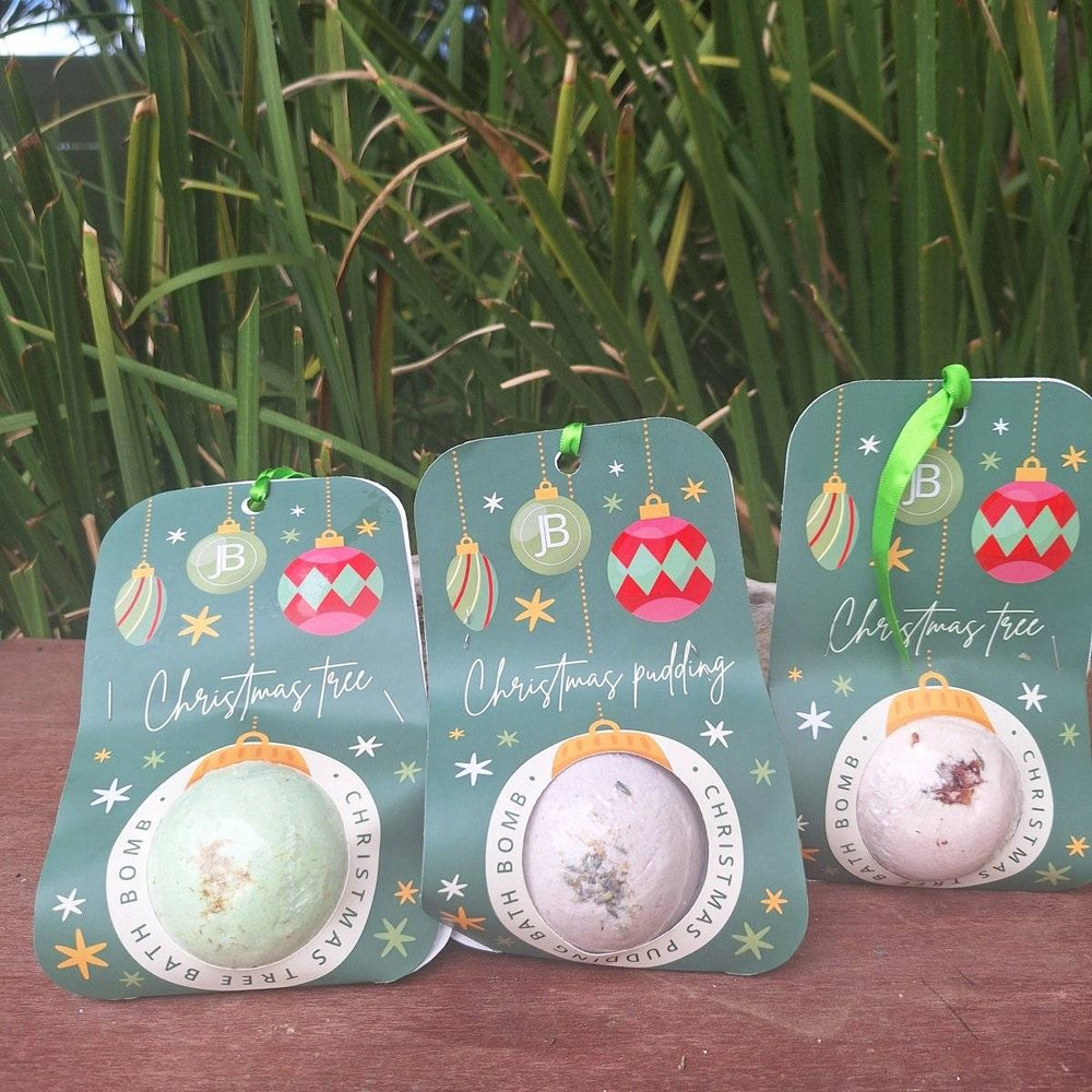 Christmas themed bath bombs with festive packaging displayed outdoors.