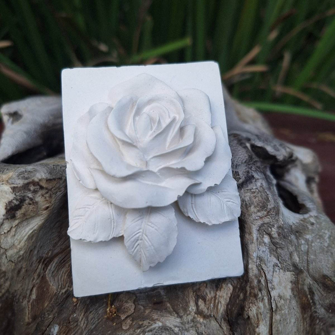 Clay diffuser stone with rose design on natural wood background.