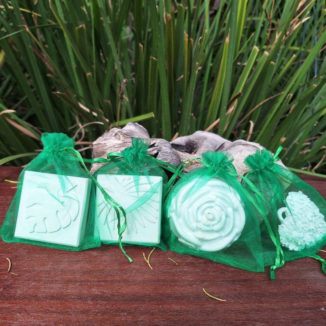 Clay diffuser stones in green mesh bags displayed on a wooden surface, surrounded by greenery.