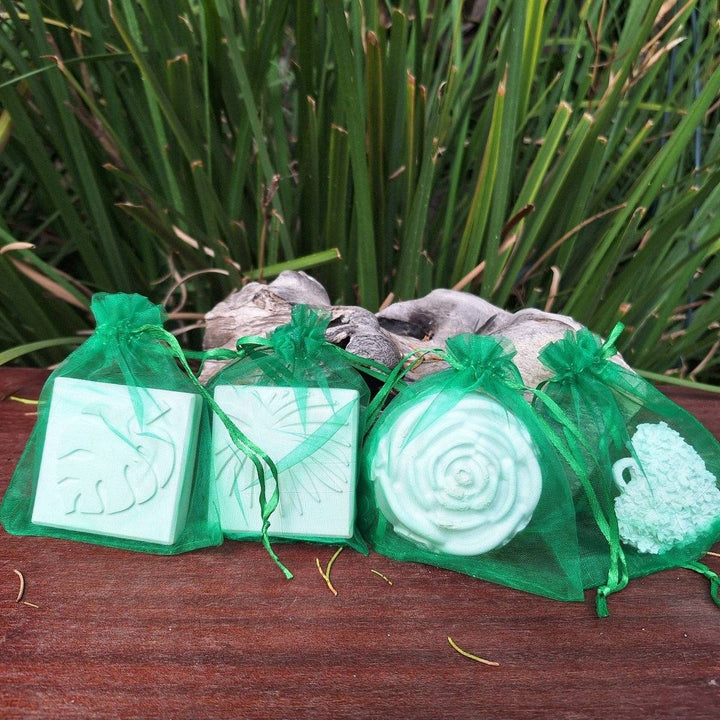 Clay diffuser stones in green mesh bags displayed on a wooden surface, surrounded by greenery.