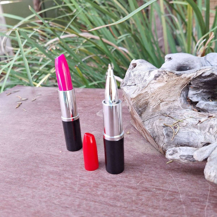 Lipstick pen with ink in vibrant pink shade on rustic wooden surface.