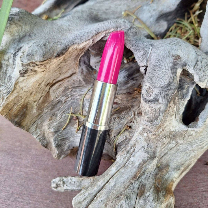 Pink lipstick pen on driftwood background.