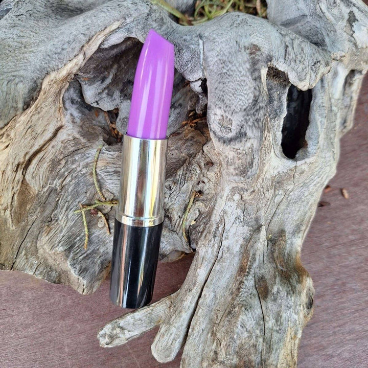 Lipstick pen with a vibrant shade resting on textured wood background.