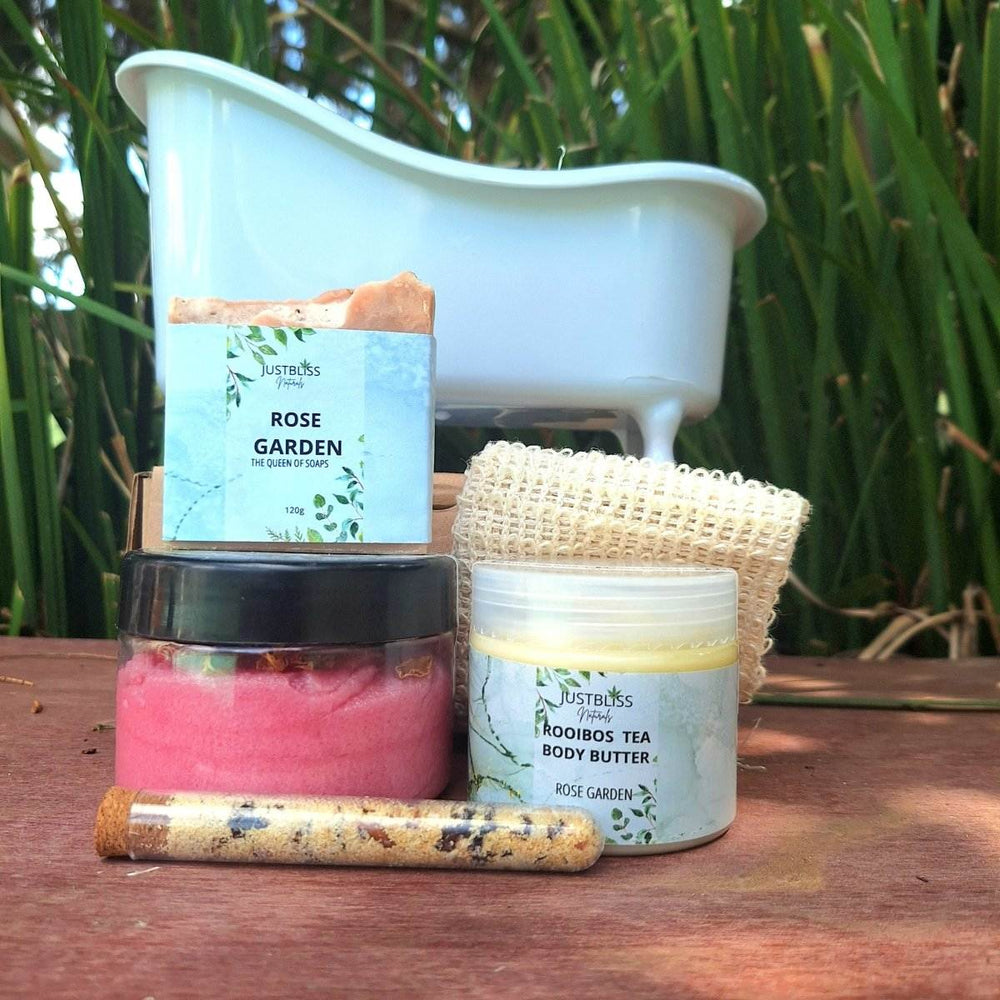GIFT BOX: Spa in a Bath set with body scrub, bath salt tube, artisan soap, sisal soap saver, and Rooibos tea body butter in front of a mini bathtub.