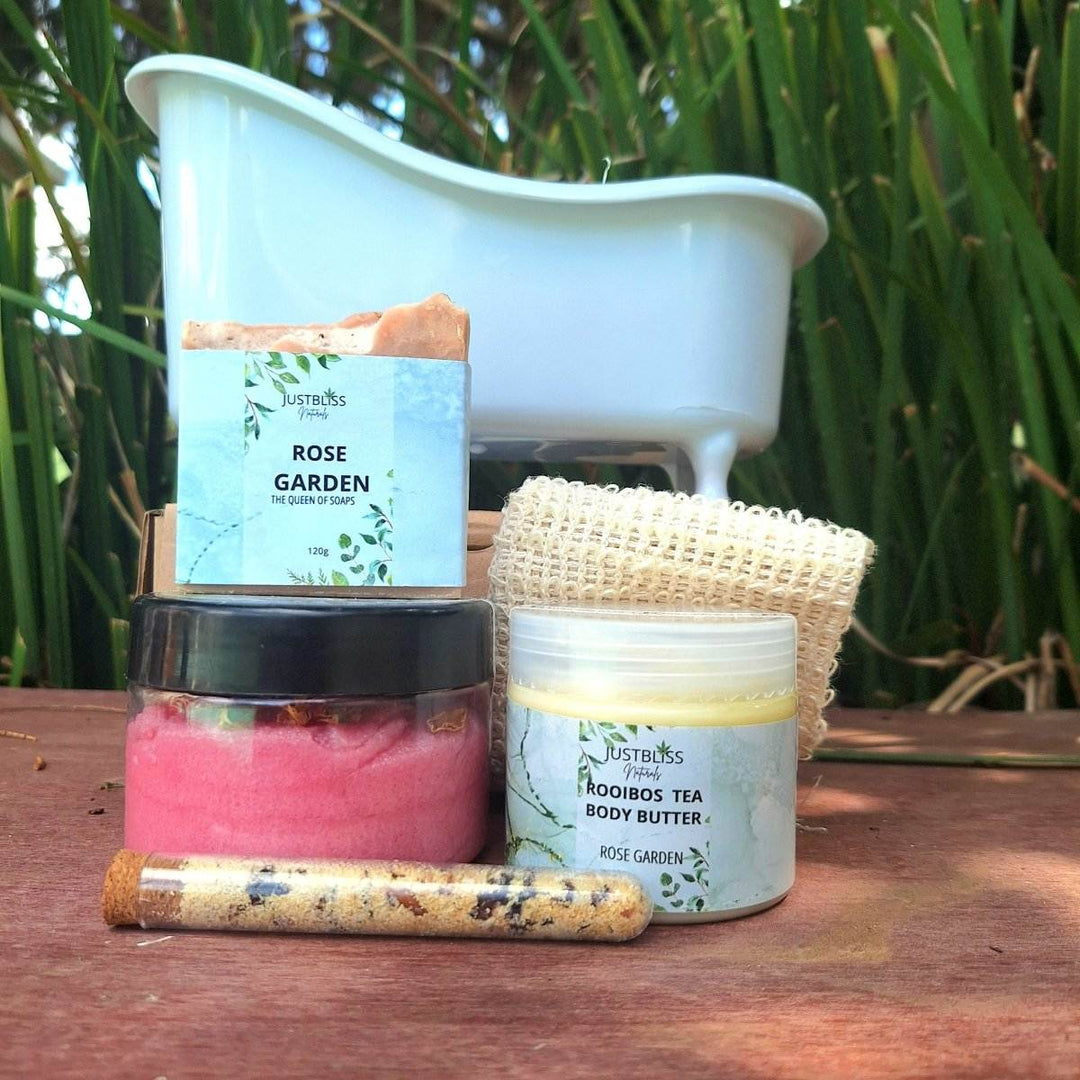 GIFT BOX: Spa in a Bath set with body scrub, bath salt tube, artisan soap, sisal soap saver, and Rooibos tea body butter in front of a mini bathtub.