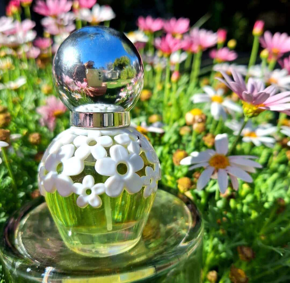 30ml floral perfume bottle with white flower design, surrounded by pink daisies.