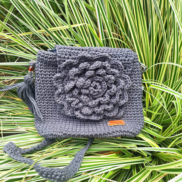 Hand-crafted handbag with crochet design, made of cotton wool, on grass background.