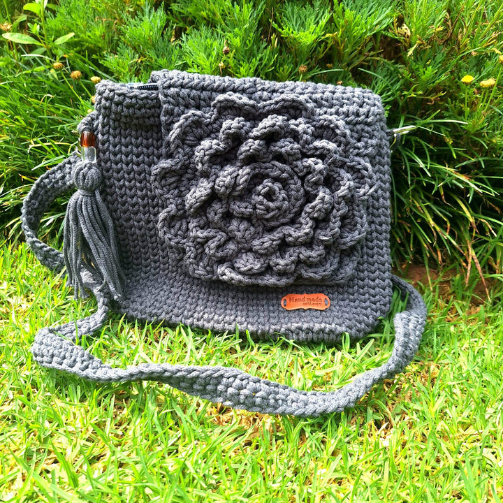 Handcrafted handbag with floral design on grass.