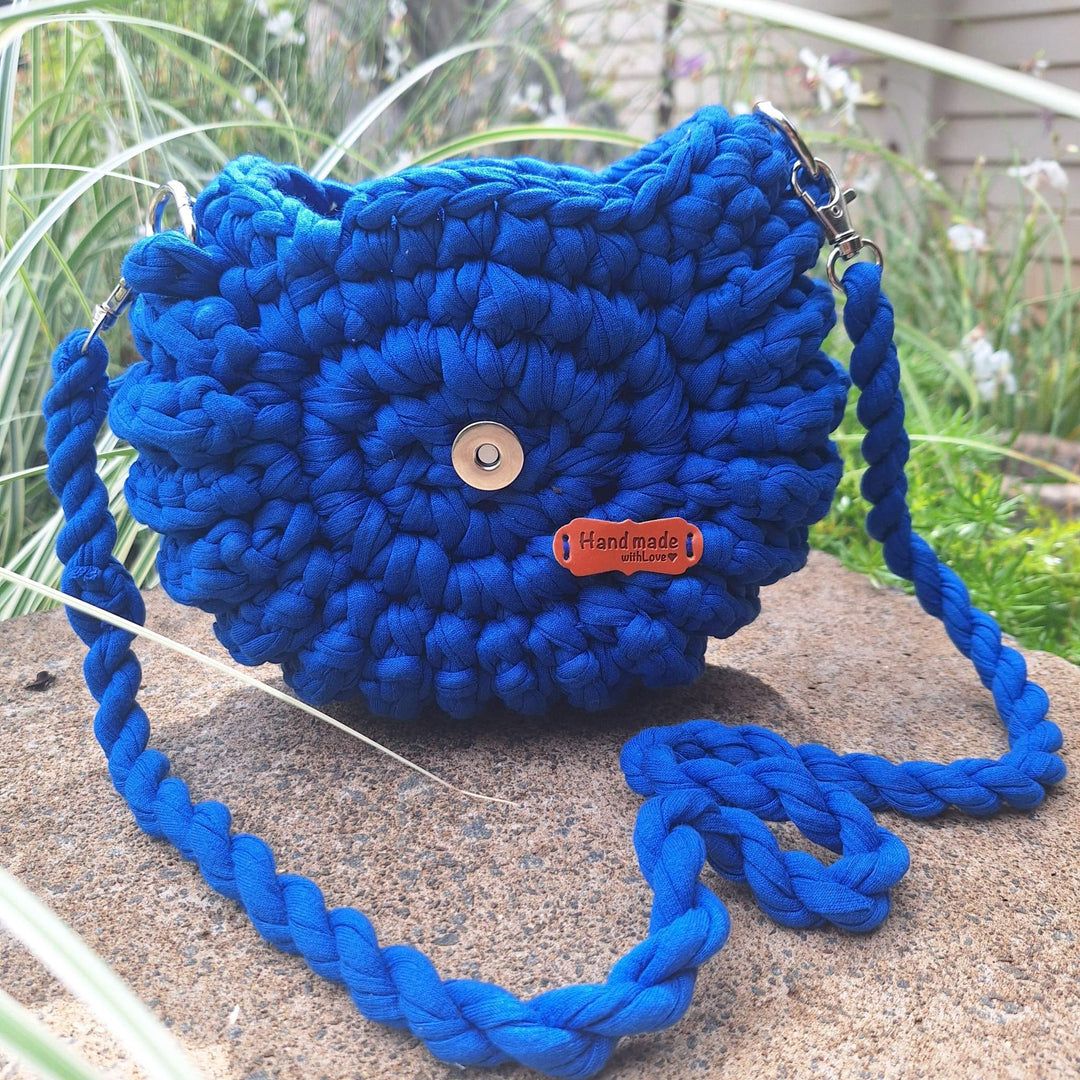 Hand-crafted handbag made of cotton wool with braided strap, displayed outdoors.