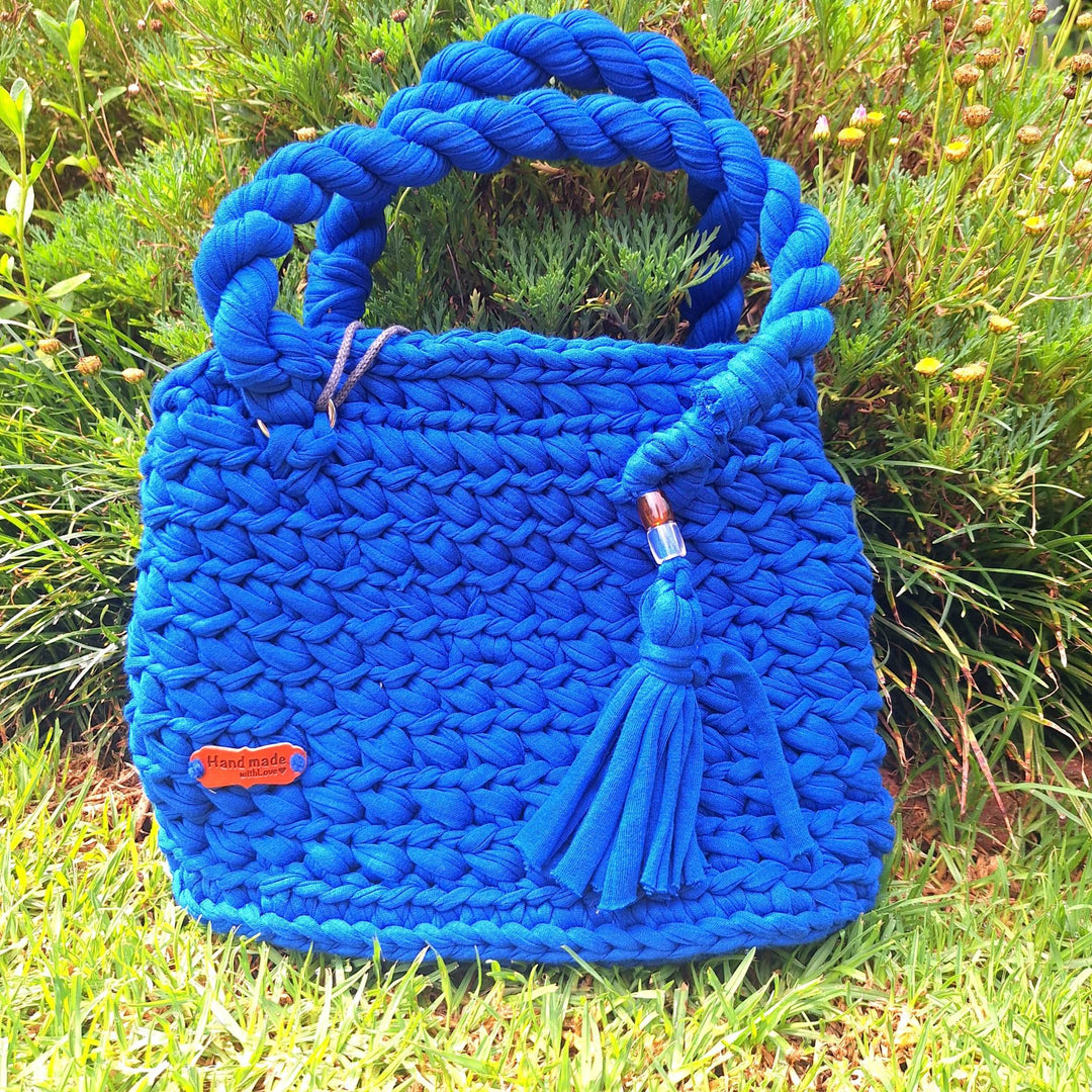 Hand-crafted handbag made of cotton wool with braided handle and tassel.
