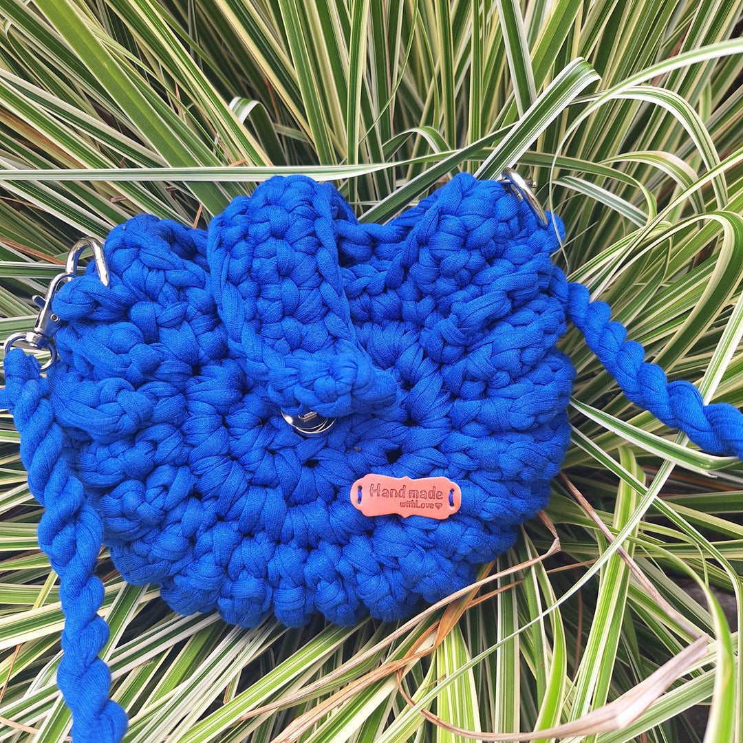 Hand-crafted handbag made from cotton wool with braided handle, displayed on grass.