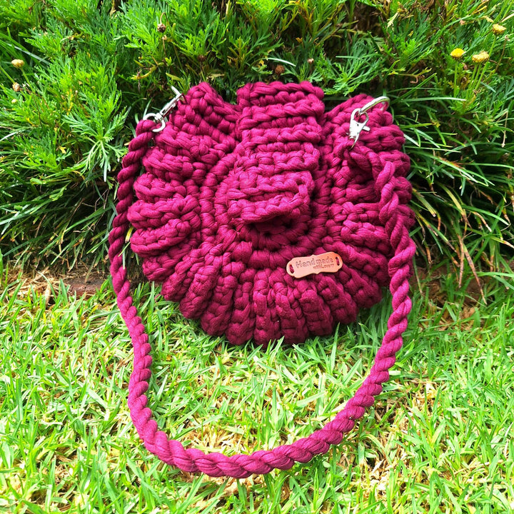 Hand-crafted handbag displayed outside on grass.