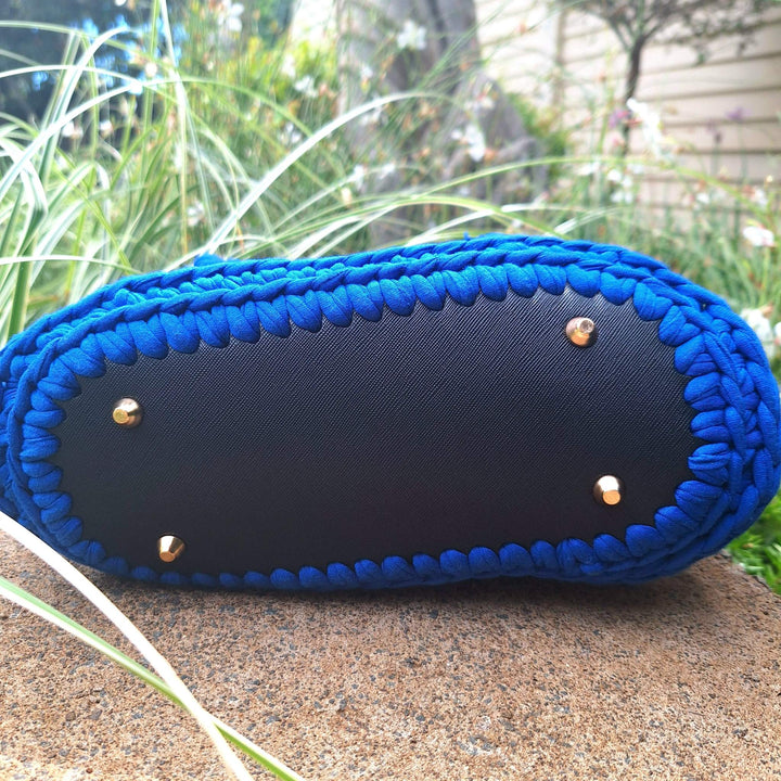 Hand-crafted handbag with blue hand-stitched detailing on the base, showcasing durability and unique craftsmanship.